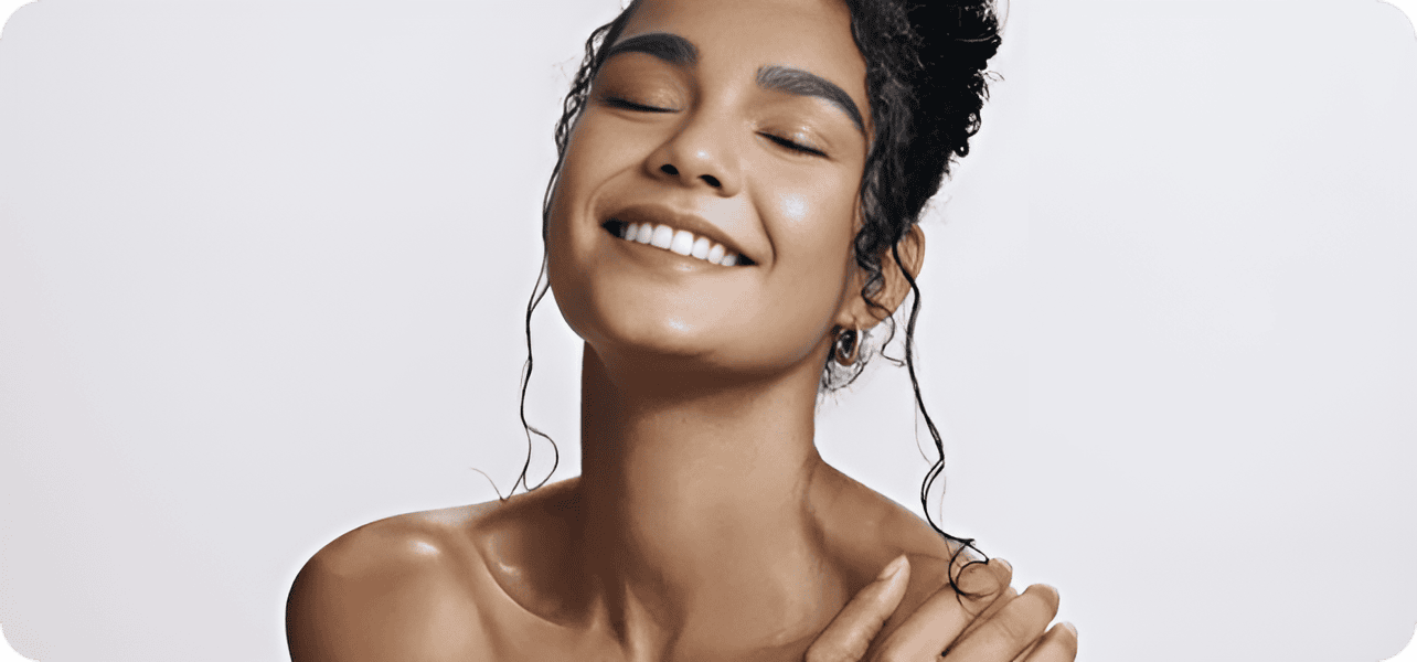 A smiling woman with closed eyes and natural makeup, showcasing confidence and happiness.